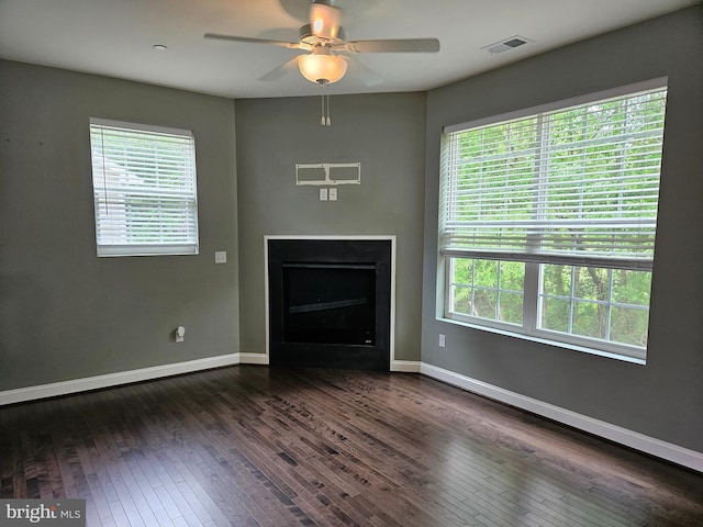 unfurnished living room with dark wood-style flooring, visible vents, and a healthy amount of sunlight