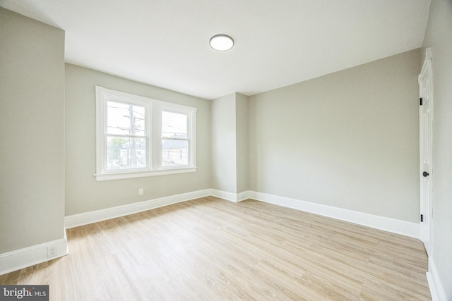 spare room with baseboards and light wood-style flooring