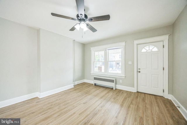 entryway featuring wood finished floors, baseboards, ceiling fan, and radiator heating unit