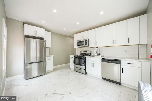 kitchen featuring baseboards, recessed lighting, marble finish floor, and appliances with stainless steel finishes