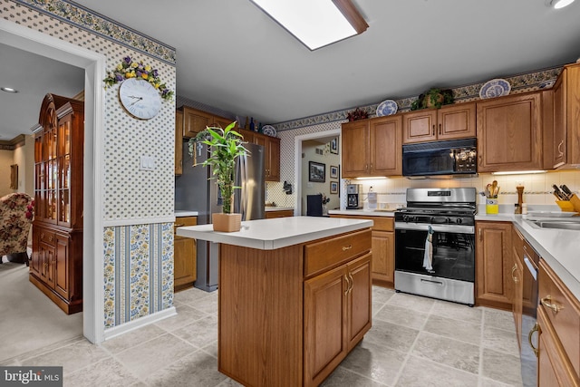 kitchen featuring brown cabinets, wallpapered walls, stainless steel appliances, light countertops, and a kitchen island