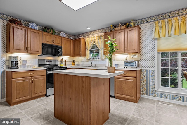 kitchen with wallpapered walls, visible vents, gas range, black microwave, and light countertops