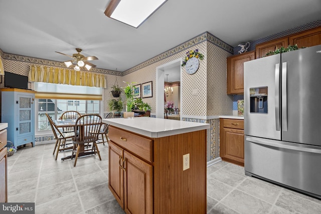 kitchen with brown cabinetry, light countertops, wallpapered walls, and stainless steel refrigerator with ice dispenser