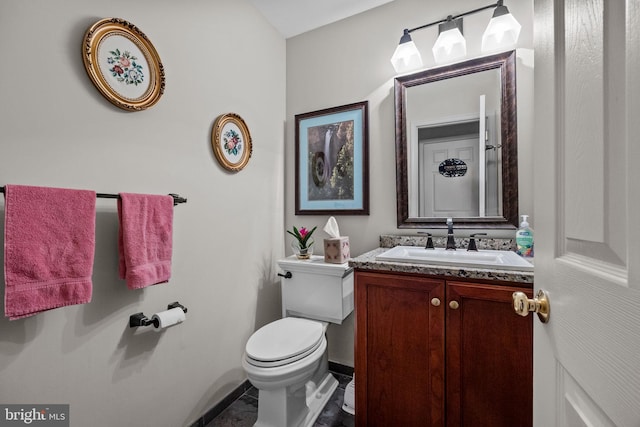 half bathroom with vanity, toilet, and baseboards