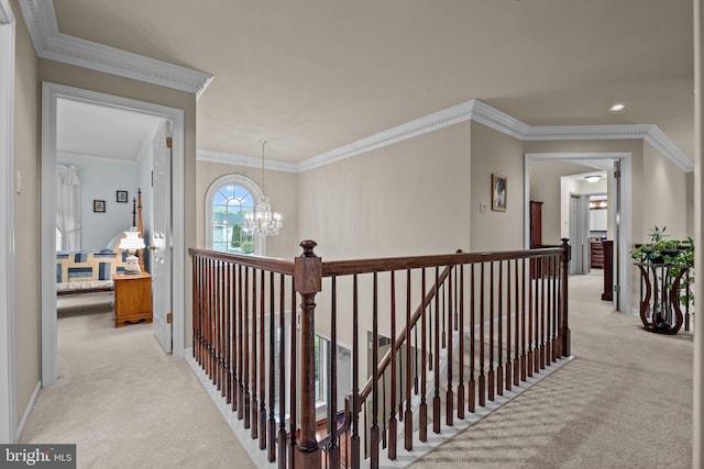 hallway with an upstairs landing, an inviting chandelier, crown molding, and light colored carpet