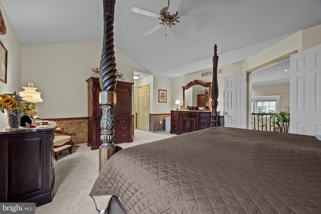 carpeted bedroom with a ceiling fan, wainscoting, and vaulted ceiling