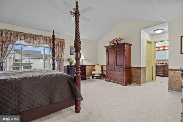 bedroom with wainscoting, ceiling fan, light colored carpet, and vaulted ceiling