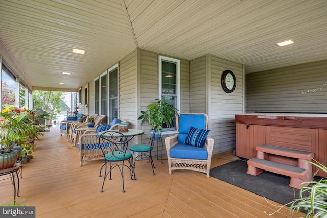 wooden deck featuring covered porch and a hot tub