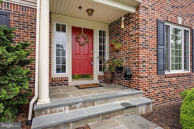 doorway to property featuring brick siding and covered porch