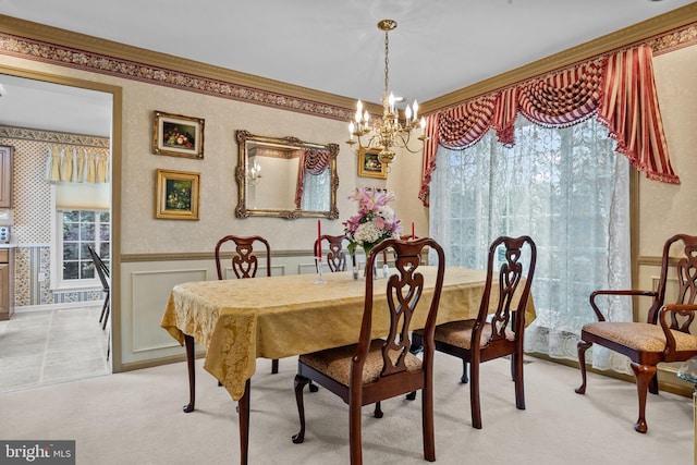 dining room featuring an inviting chandelier, light carpet, wainscoting, and ornamental molding