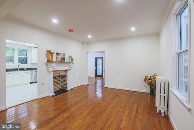 3614 Keene Ave, Baltimore, MD 21214 - unfurnished living room with radiator heating unit, ornamental molding, a sink, wood finished floors, and a brick fireplace