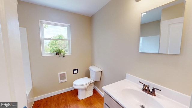 full bath featuring toilet, wood finished floors, baseboards, vanity, and heating unit