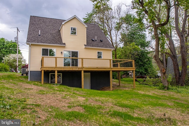 rear view of property featuring a deck, roof with shingles, and a yard