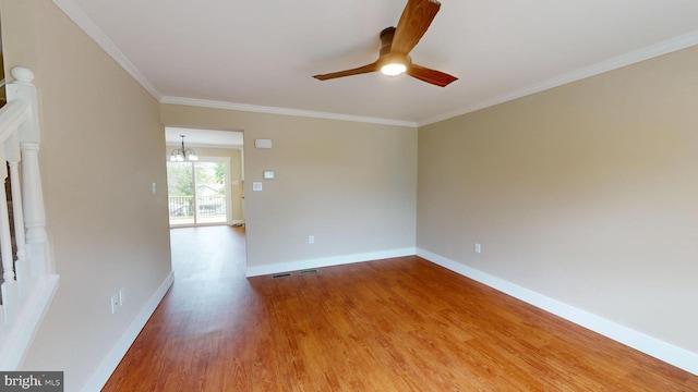 unfurnished room with ceiling fan, wood finished floors, baseboards, crown molding, and a chandelier