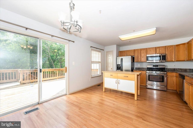 kitchen featuring stainless steel appliances, a chandelier, light wood-style floors, and pendant lighting