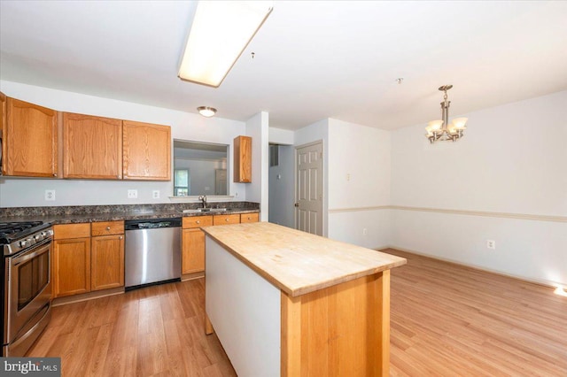 kitchen with stainless steel appliances, a sink, light wood-type flooring, a chandelier, and a kitchen island