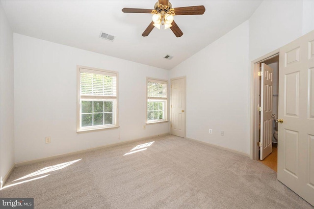 spare room with vaulted ceiling, light colored carpet, a ceiling fan, and baseboards