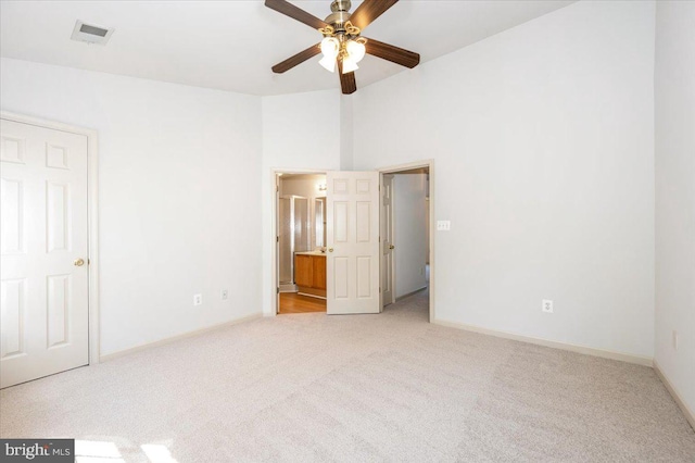 unfurnished bedroom featuring light carpet, baseboards, and ensuite bath