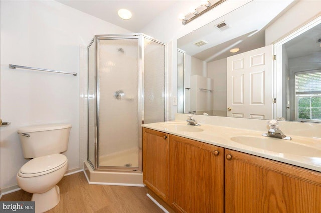 full bathroom featuring a shower stall, wood finished floors, toilet, and double vanity