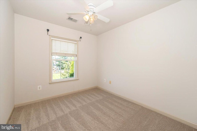 spare room featuring light colored carpet, baseboards, and a ceiling fan