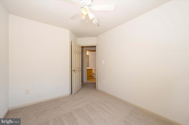 spare room featuring light colored carpet, baseboards, and a ceiling fan