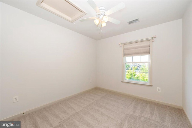 empty room featuring light colored carpet, baseboards, a ceiling fan, and attic access