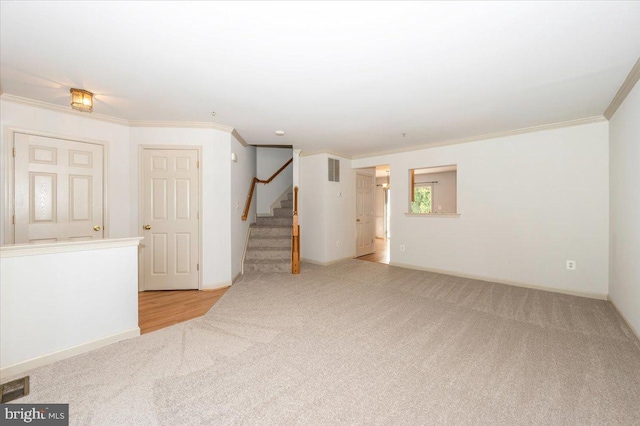 unfurnished room featuring carpet floors, crown molding, stairway, and baseboards