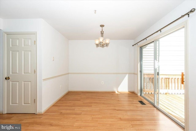 unfurnished dining area featuring a chandelier, light wood-style flooring, and baseboards