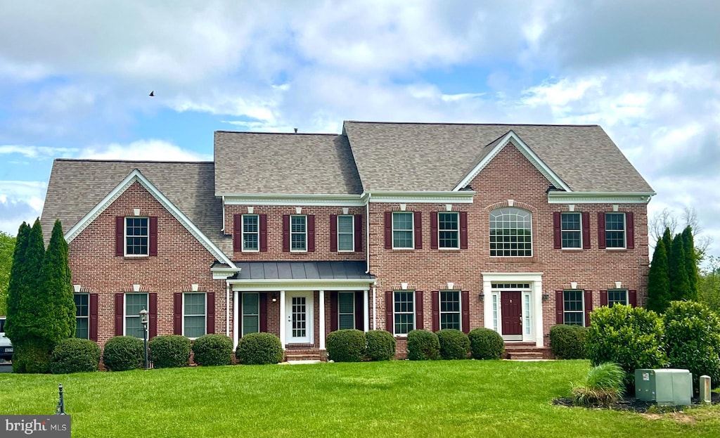 view of front of home with brick siding, a front lawn, and roof with shingles