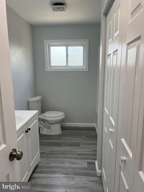 bathroom featuring vanity, baseboards, toilet, and wood finished floors