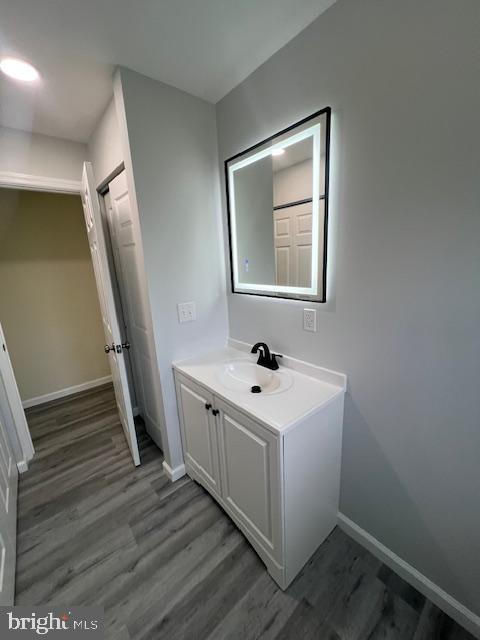 bathroom featuring baseboards, wood finished floors, and vanity