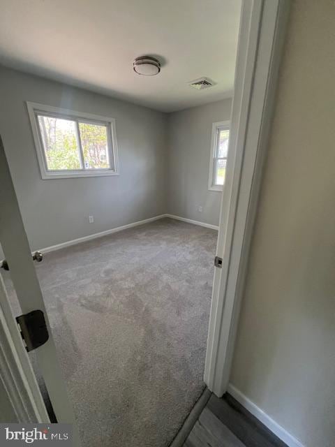 unfurnished bedroom with carpet flooring, baseboards, and visible vents