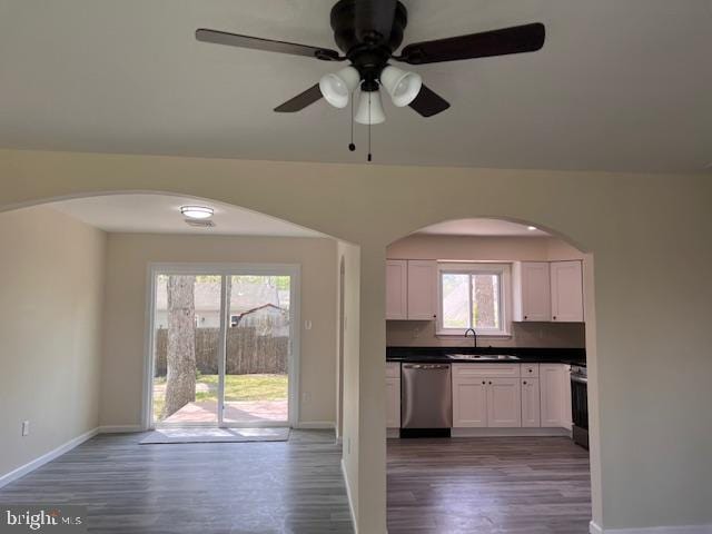 kitchen with a sink, arched walkways, wood finished floors, and stainless steel appliances
