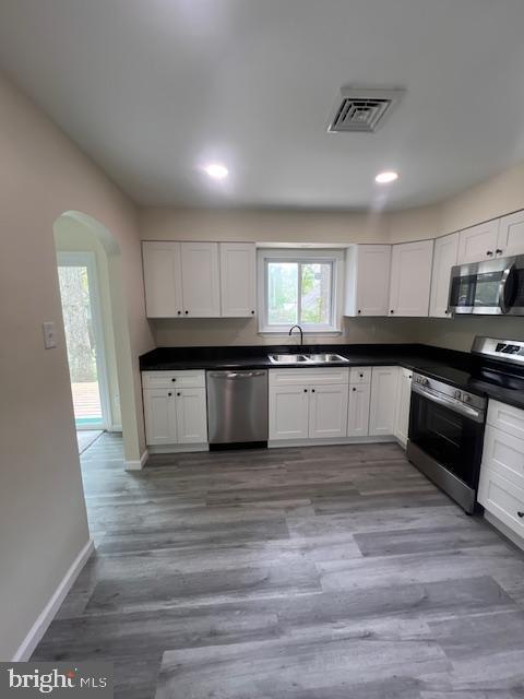 kitchen with appliances with stainless steel finishes, a sink, arched walkways, plenty of natural light, and visible vents