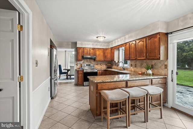 6122 Wallingford Way, Mechanicsburg, PA 17050 - kitchen with under cabinet range hood, a breakfast bar, a sink, tasteful backsplash, and appliances with stainless steel finishes