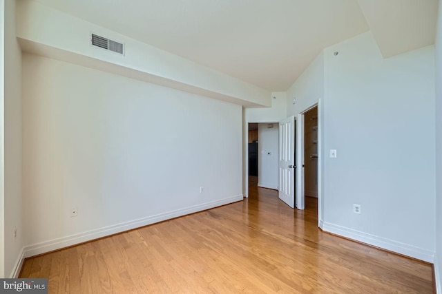 empty room with baseboards, visible vents, and light wood finished floors