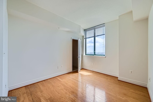 unfurnished room featuring baseboards and light wood-style floors