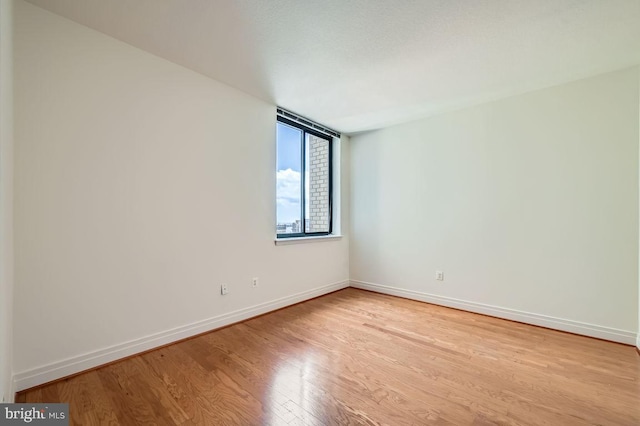 spare room with baseboards and wood finished floors