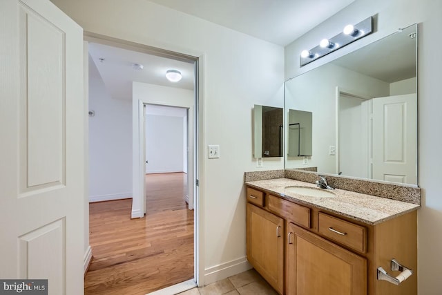 bathroom featuring baseboards, wood finished floors, and vanity