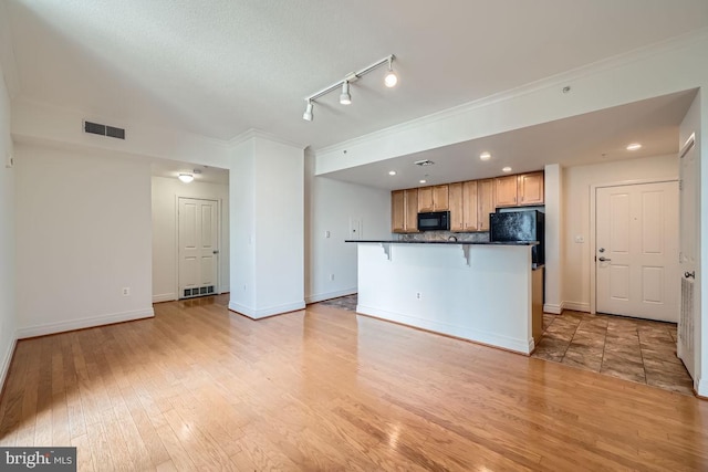 kitchen with dark countertops, black appliances, light wood-type flooring, and visible vents