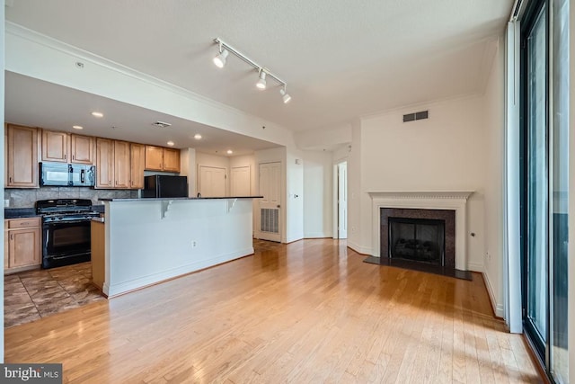 kitchen with light wood-style floors, dark countertops, black appliances, and visible vents