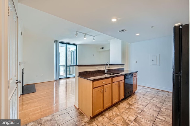 kitchen with visible vents, a sink, baseboards, black appliances, and dark stone counters