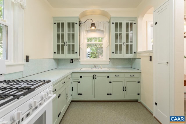 kitchen with a sink, decorative backsplash, white range with gas stovetop, and light countertops