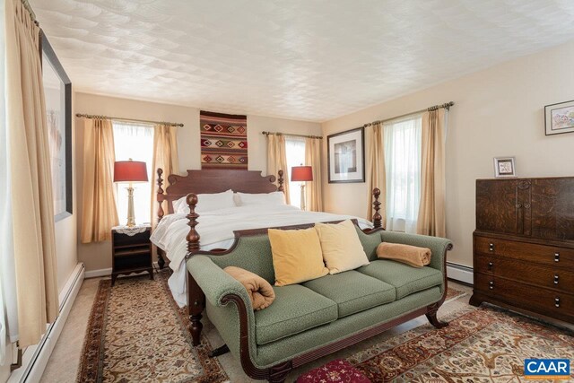 carpeted bedroom with baseboards, multiple windows, and baseboard heating