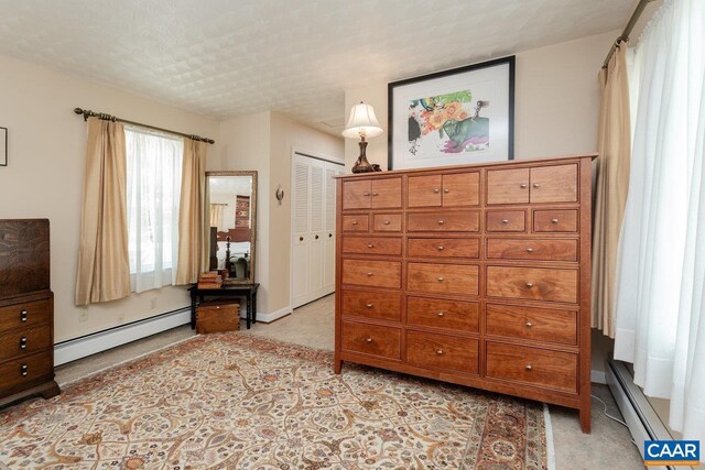 bedroom with light colored carpet, baseboards, baseboard heating, and a closet
