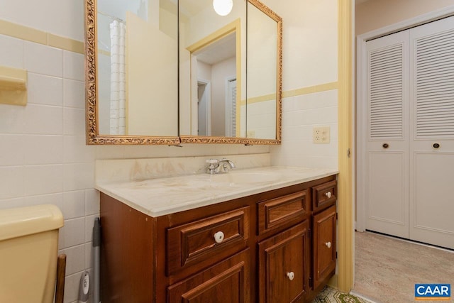 full bathroom featuring tile walls, vanity, and toilet