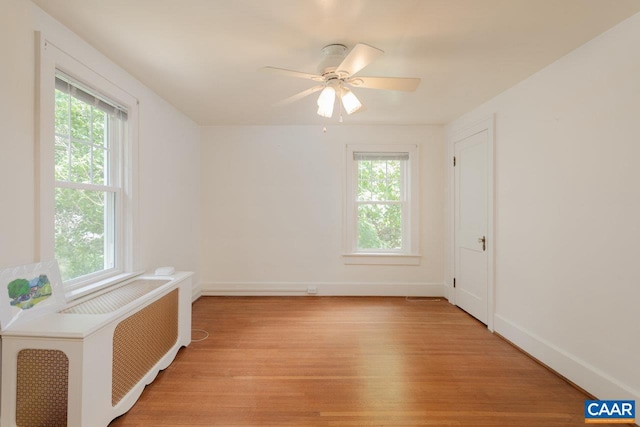 spare room featuring a ceiling fan, baseboards, plenty of natural light, and light wood-type flooring