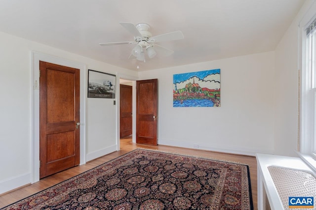 unfurnished bedroom with a ceiling fan, baseboards, and light wood-type flooring