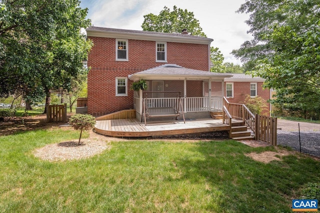 rear view of house featuring a lawn, a wooden deck, and brick siding