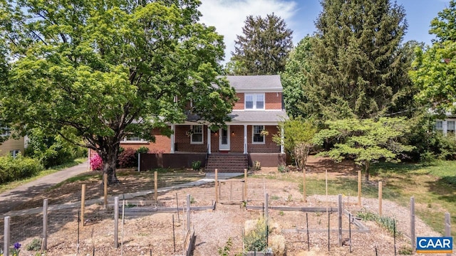 traditional-style house featuring a porch, brick siding, and a vegetable garden